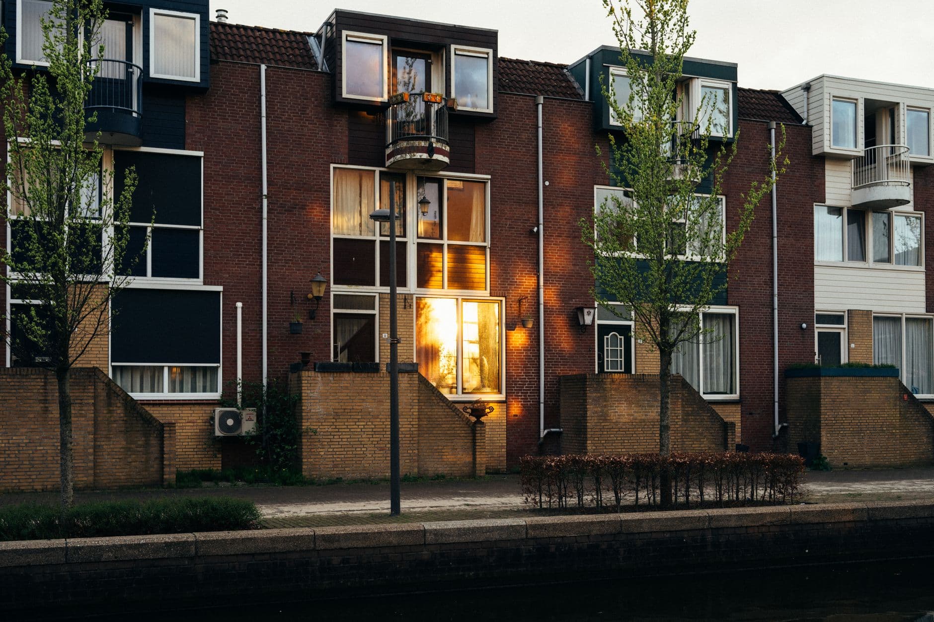 Rij bakstenen woningen aan het water bij zonsondergang