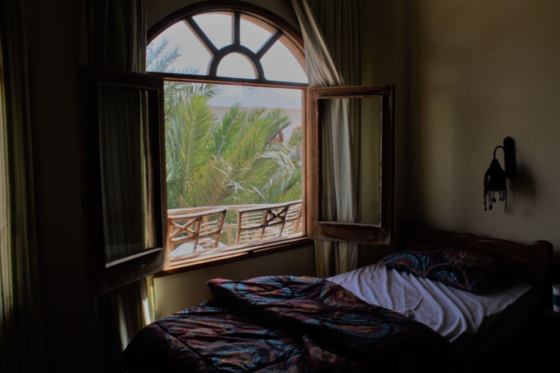 Slaapkamer met een openstaand raam en een onopgemaakt bed