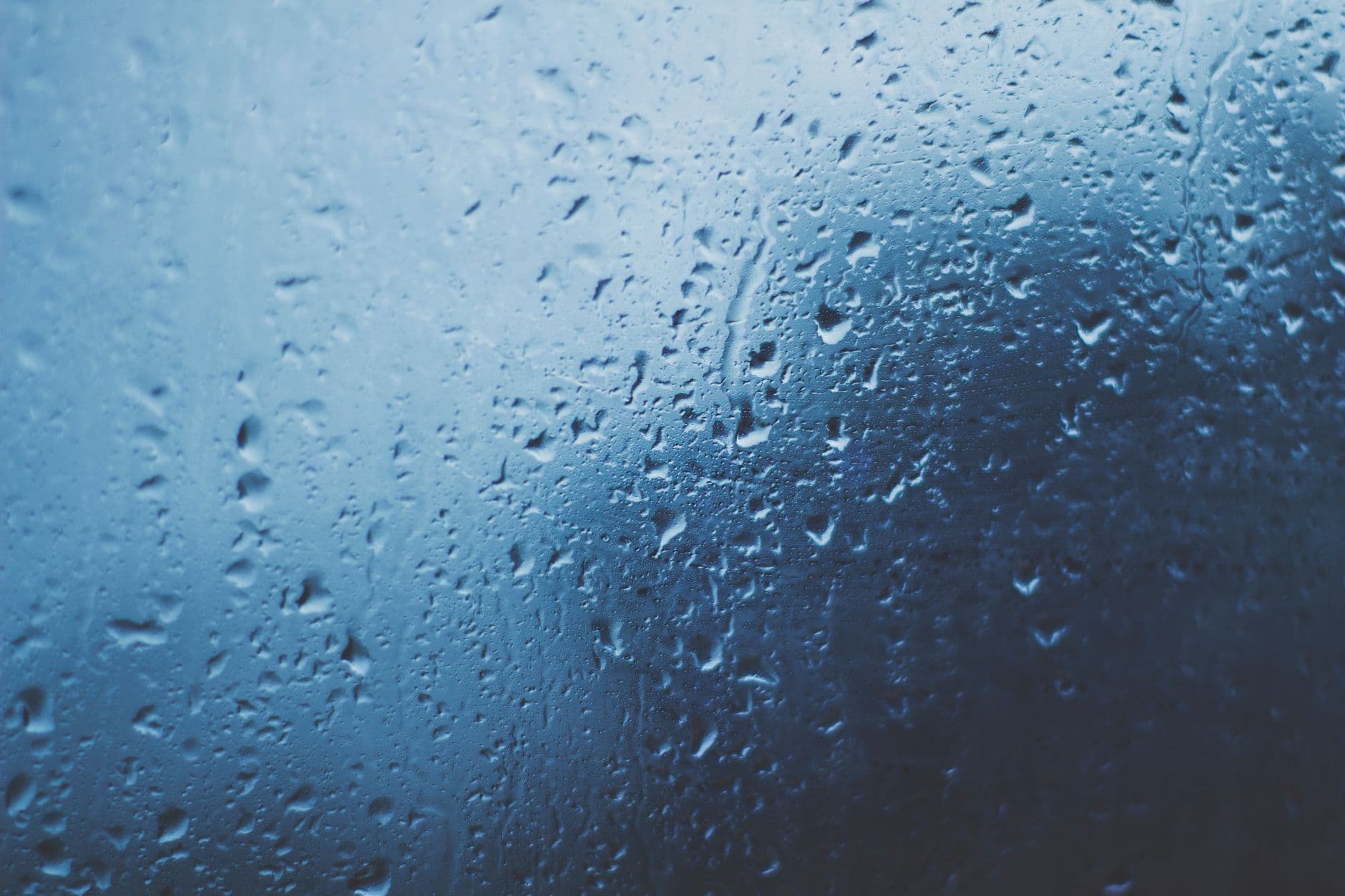 Waterdruppels op een raam met een blauwe achtergrond