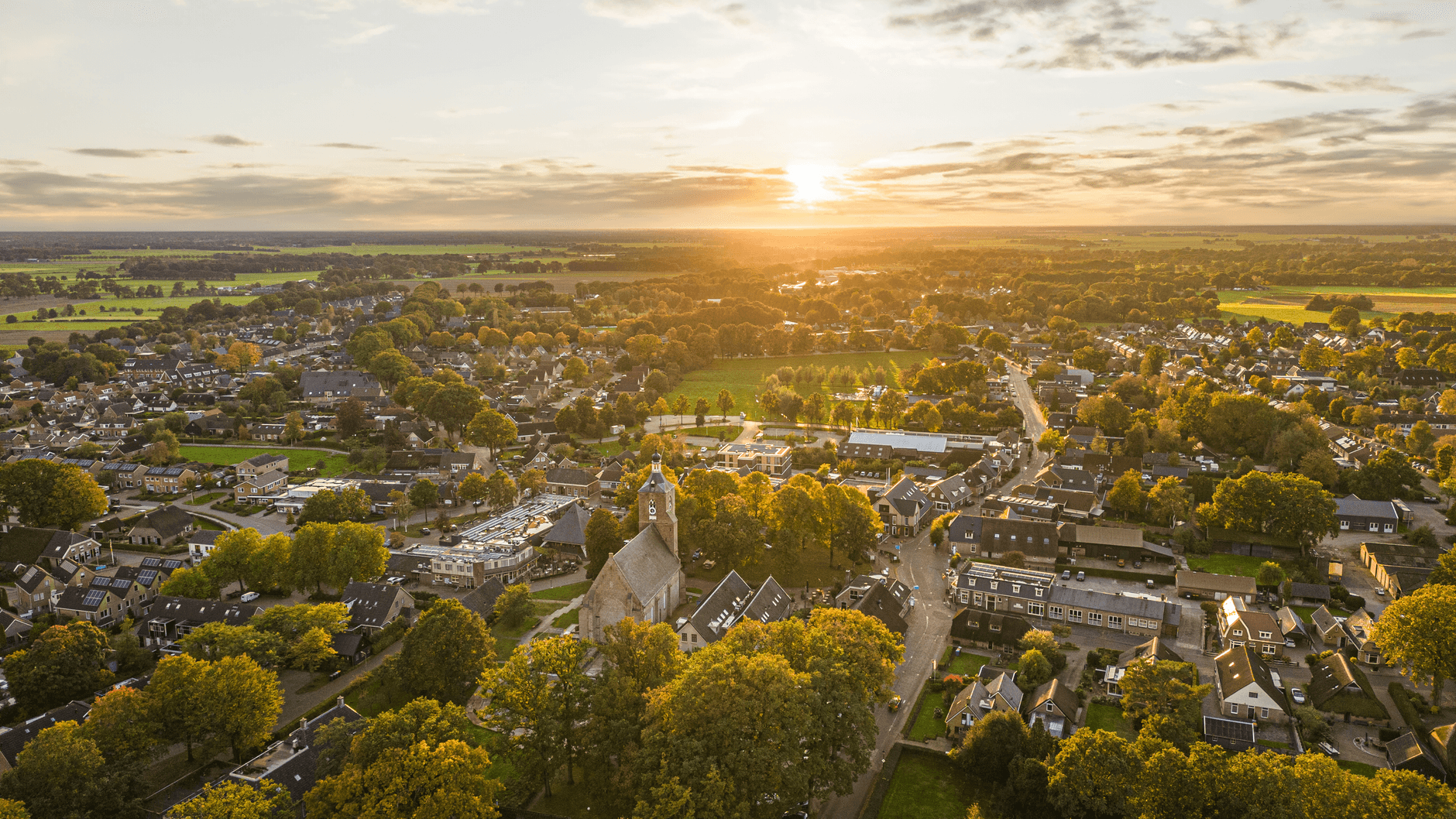 Luchtfoto van een dorp met bomen en daken bij zonsondergang
