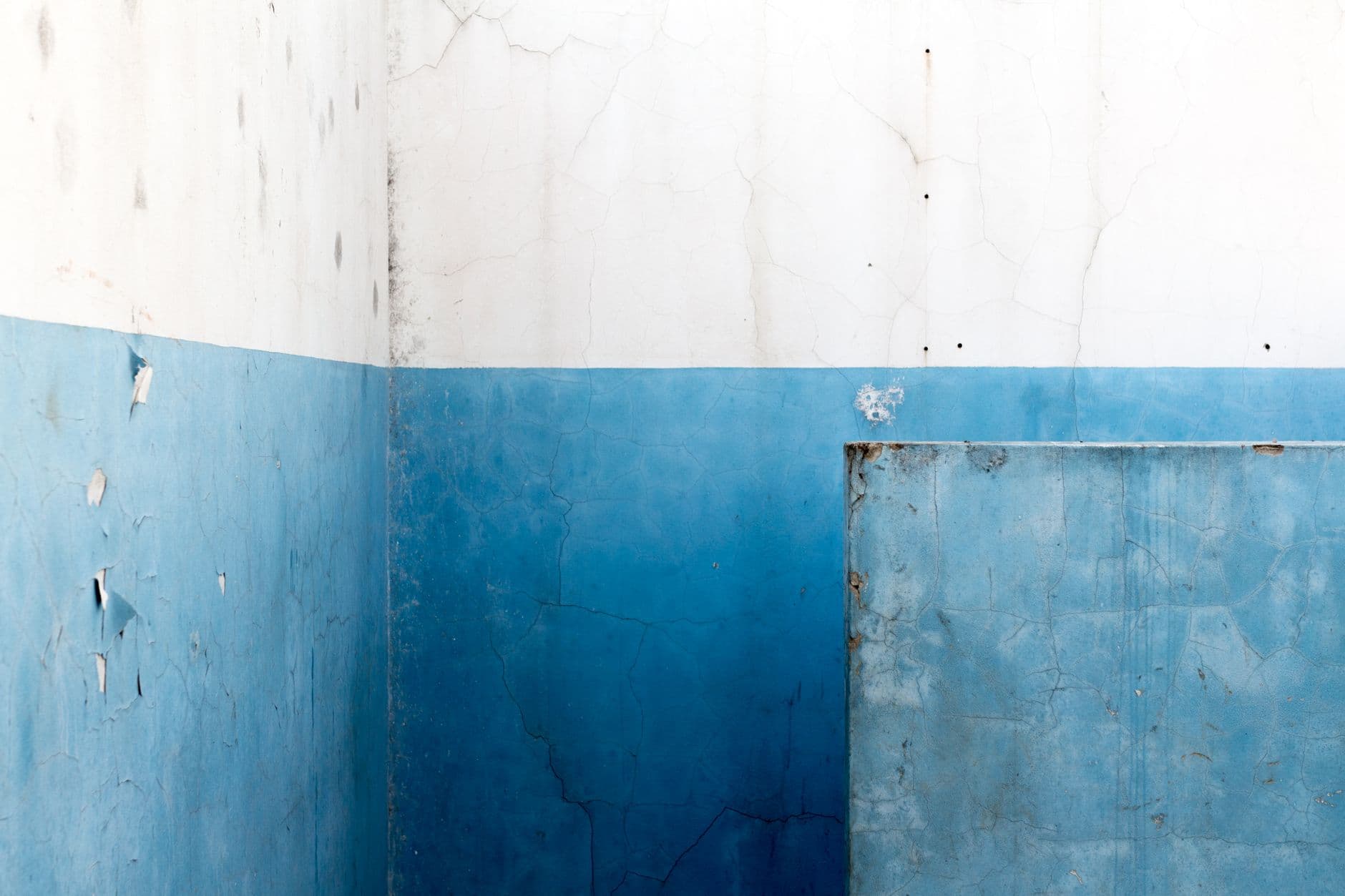 Muur met afgebladderde blauwe verf onderaan