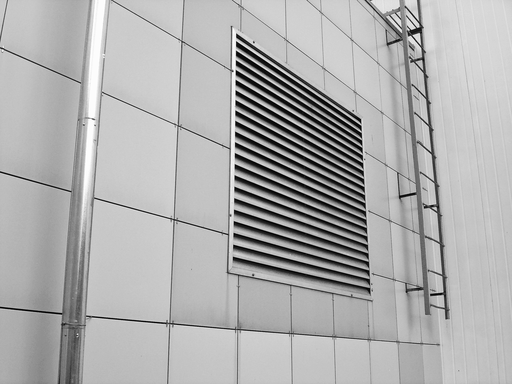 Groot ventilatierooster in een gevel met metalen panelen