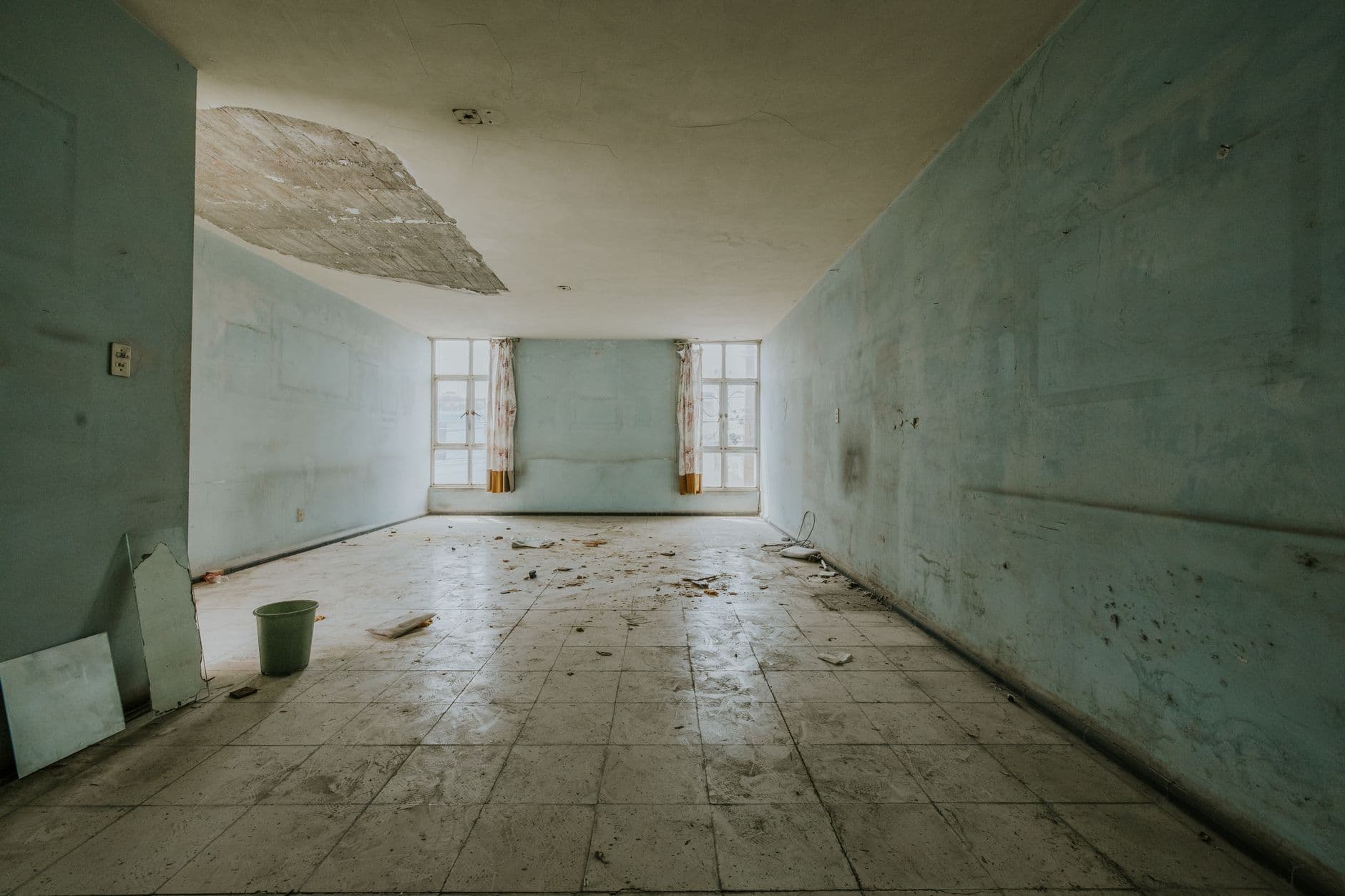 Lege ruimte met een beschadigd plafond en losgekomen pleisterwerk