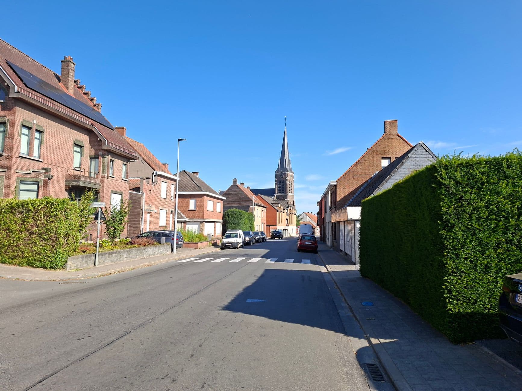 Straat met bakstenen huizen en een kerktoren in de verte