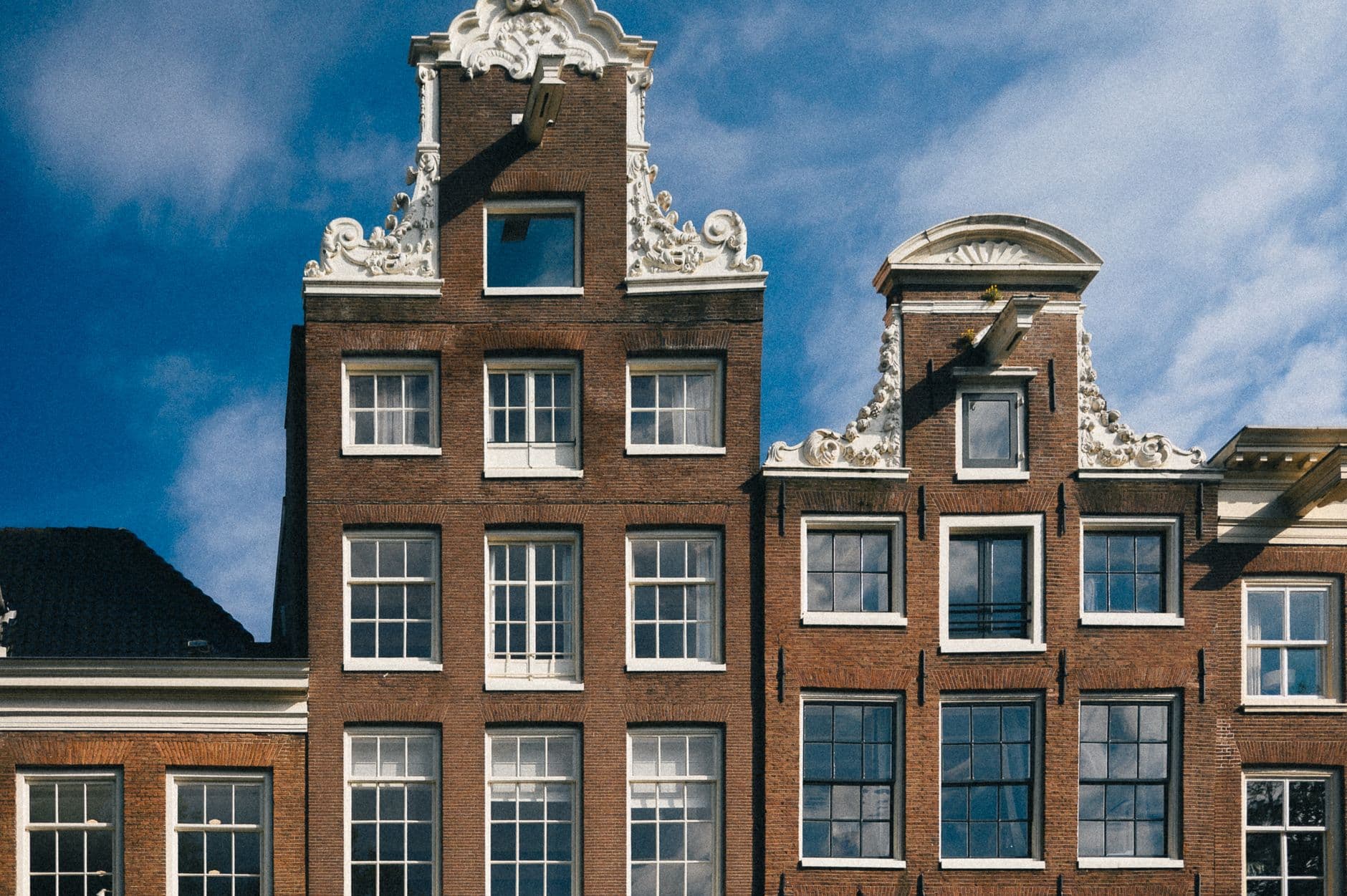 Bakstenen gevels met witte krullen en sierlijsten tegen een blauwe lucht