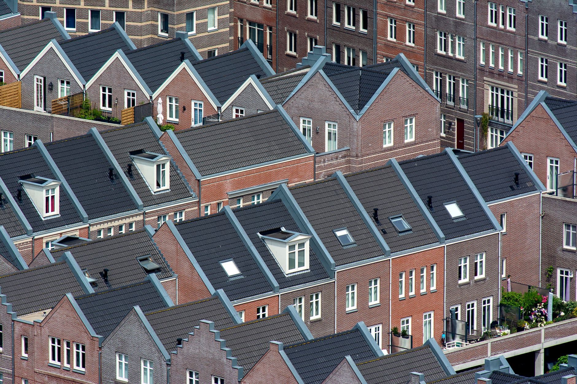 Daken van een nieuwbouwwijk met bakstenen rijwoningen