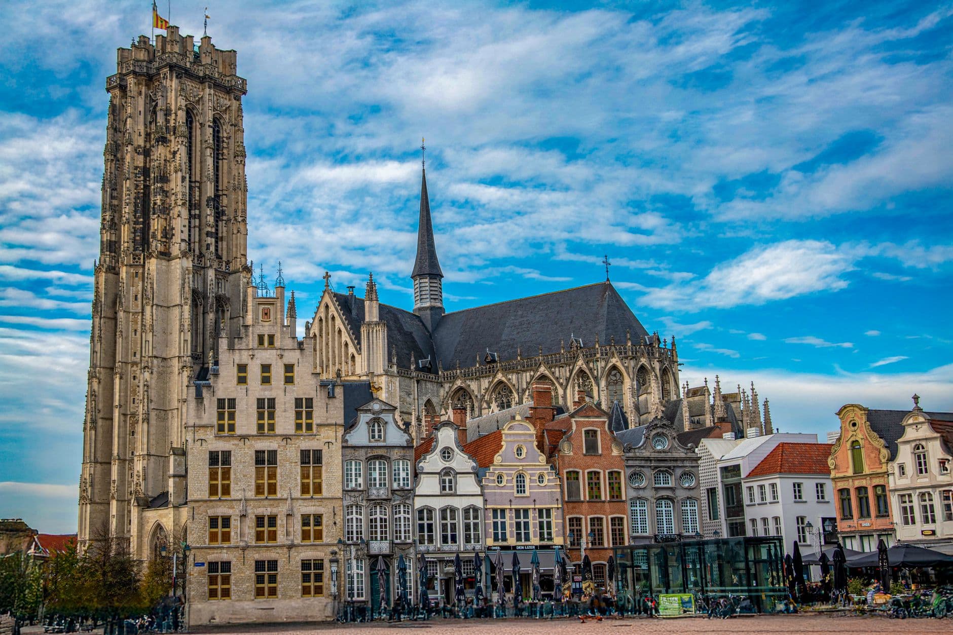 Toren en gevels aan de markt van Mechelen onder een blauwe lucht