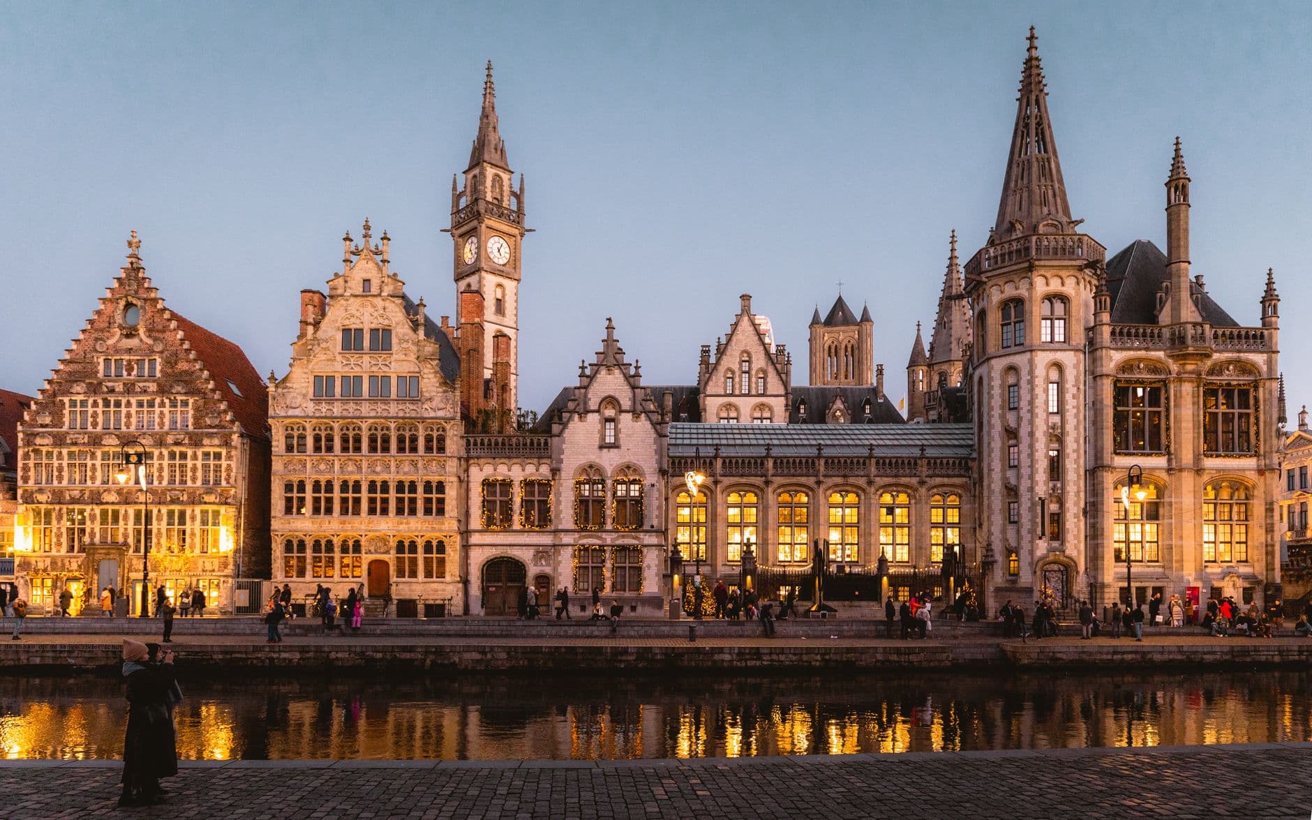 Verlichte historische gevels aan het water in Gent bij valavond