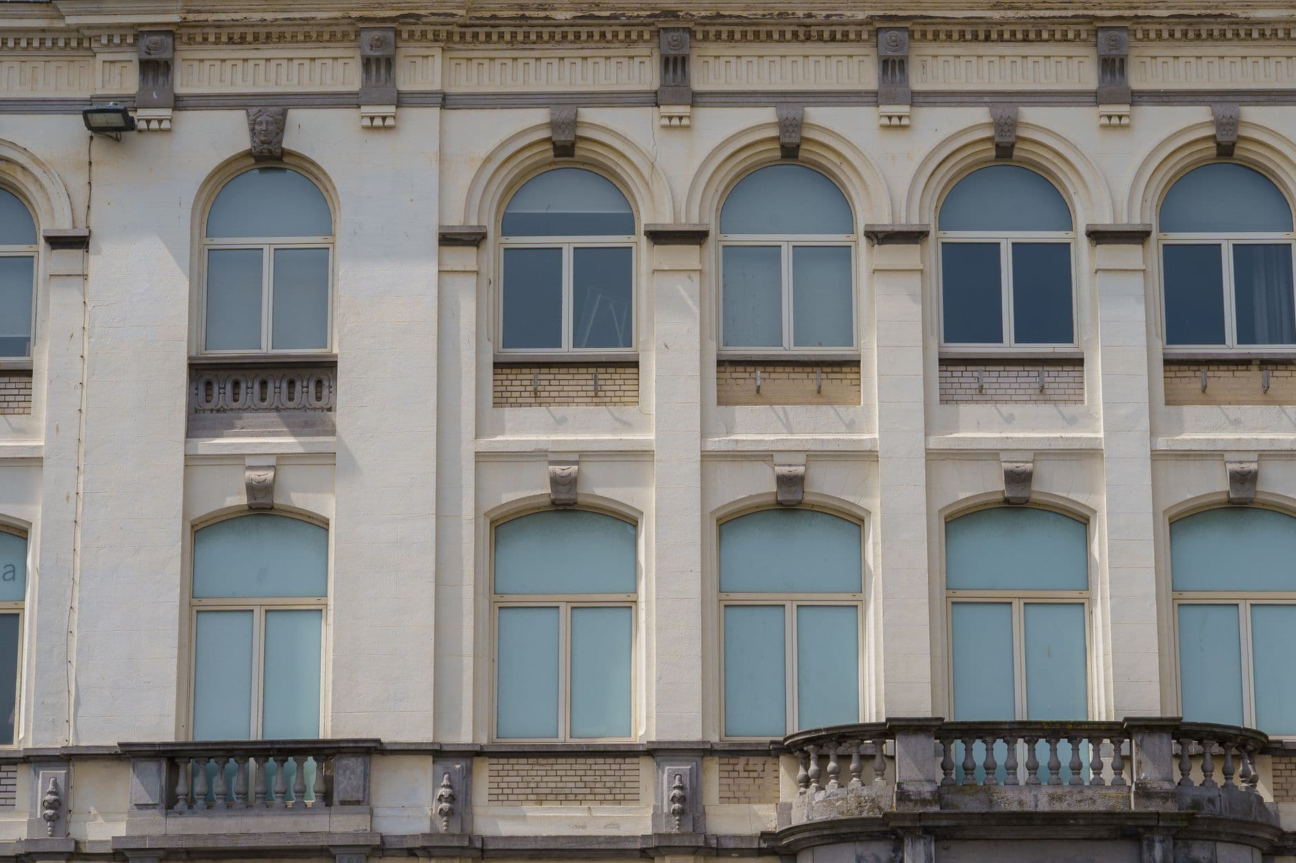 Witte gevel met boogramen en een balkon in Oostende